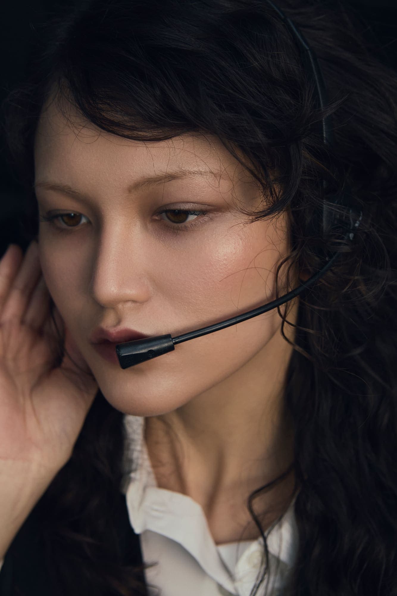 Close portrait of a woman wearing a telephone headset with her hand to her ear
