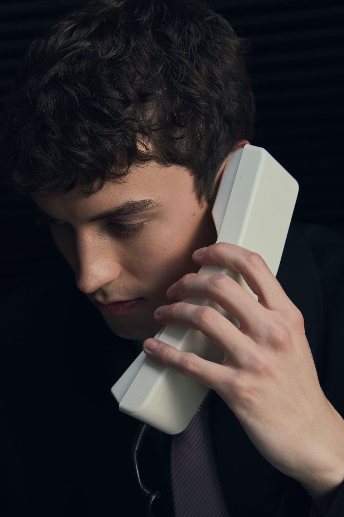 Close portrait of a man listening intently on a beige phone handset
