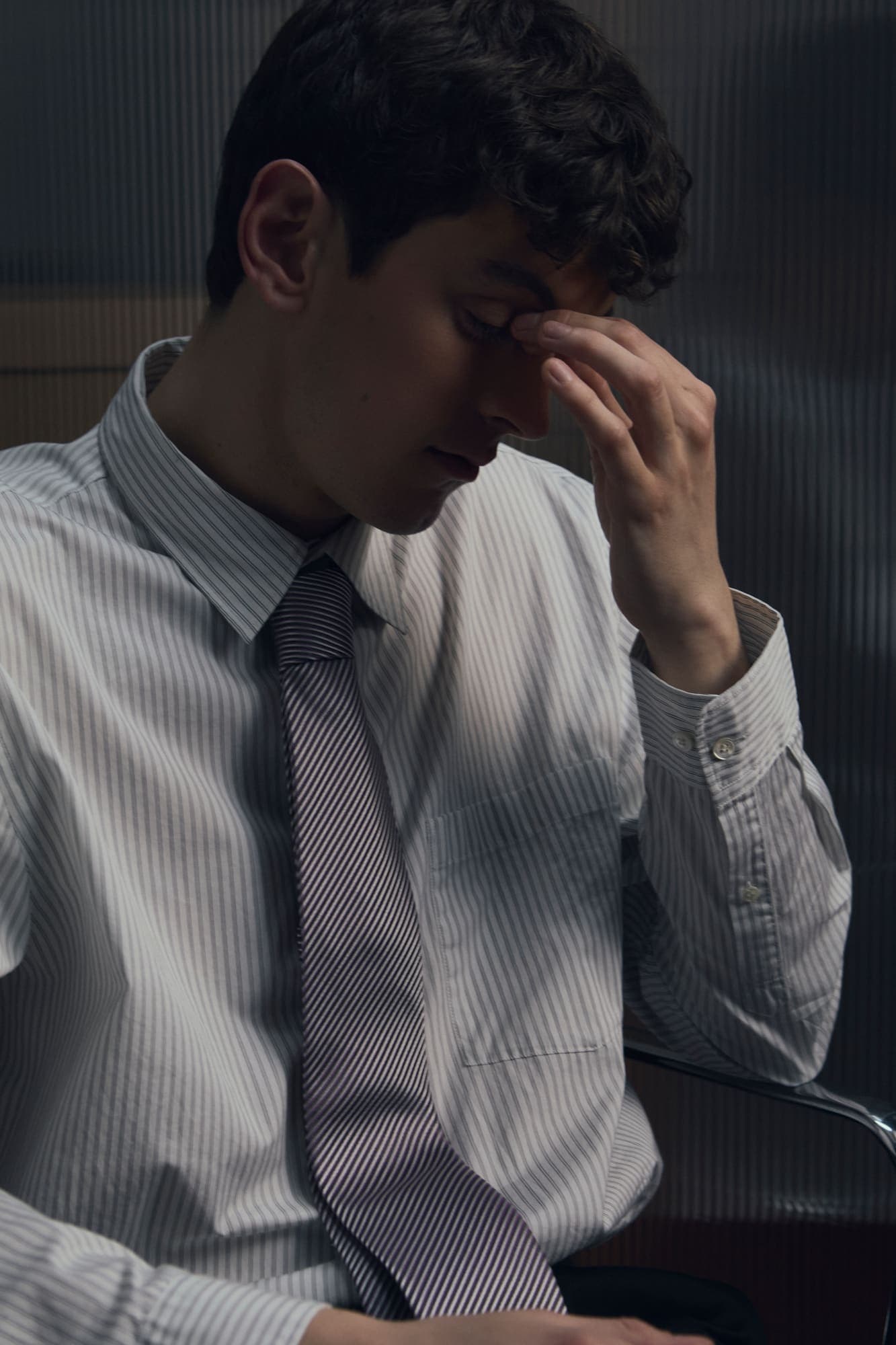 A man pinching the bridge of his nose in fatigue at his desk