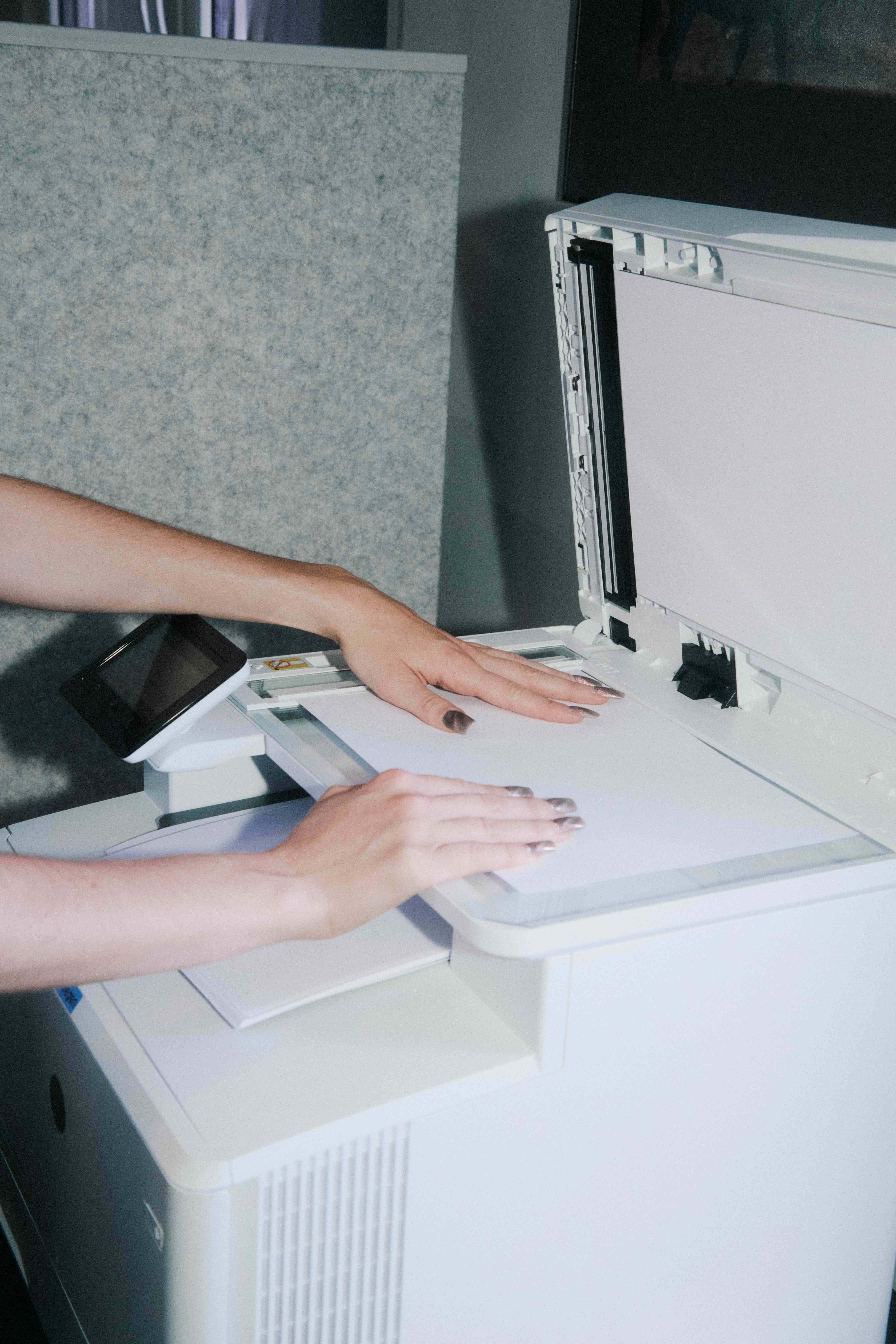 Hands placing a sheet on a photocopier glass.