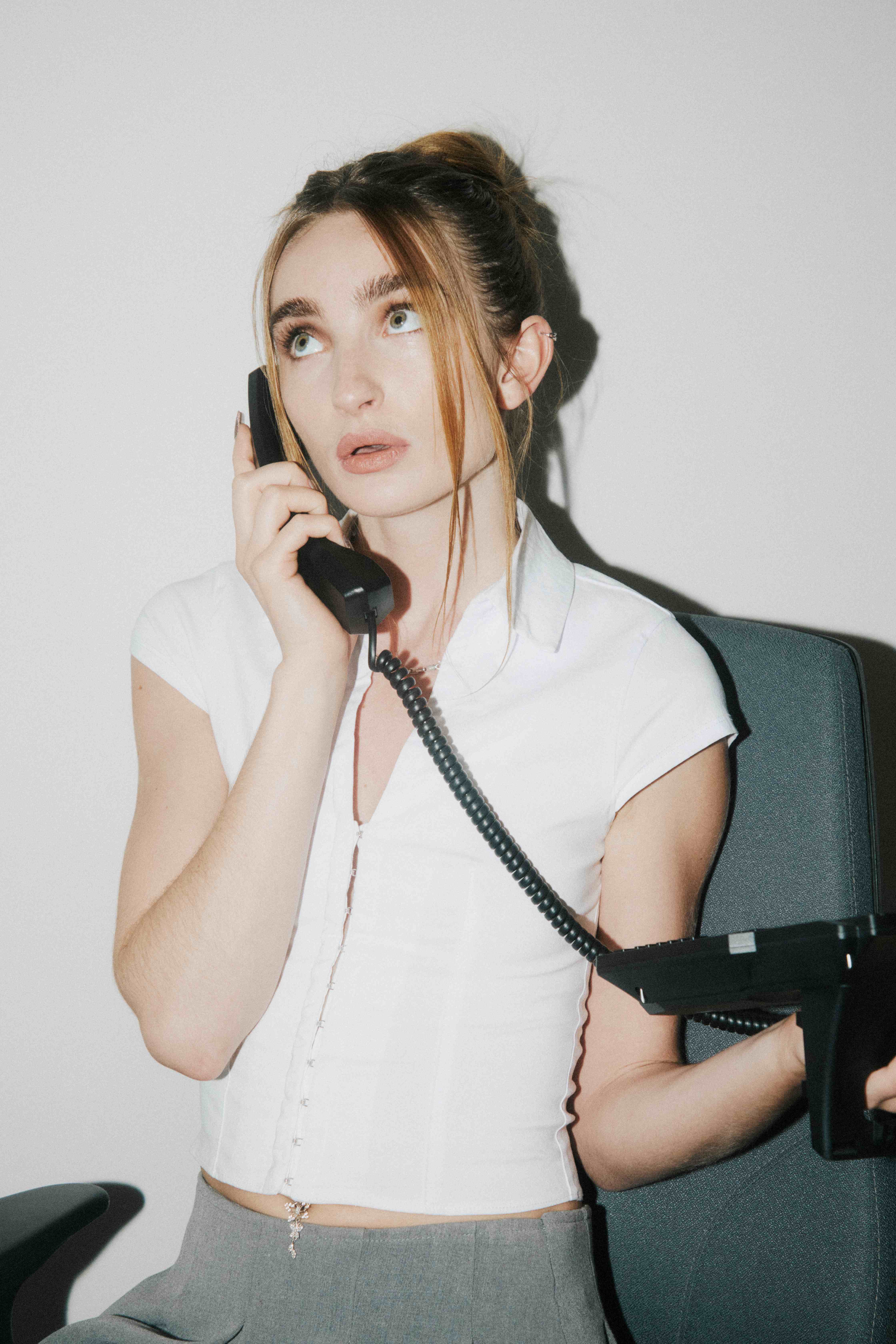 A woman at her desk reacting to an urgent call on a corded office phone