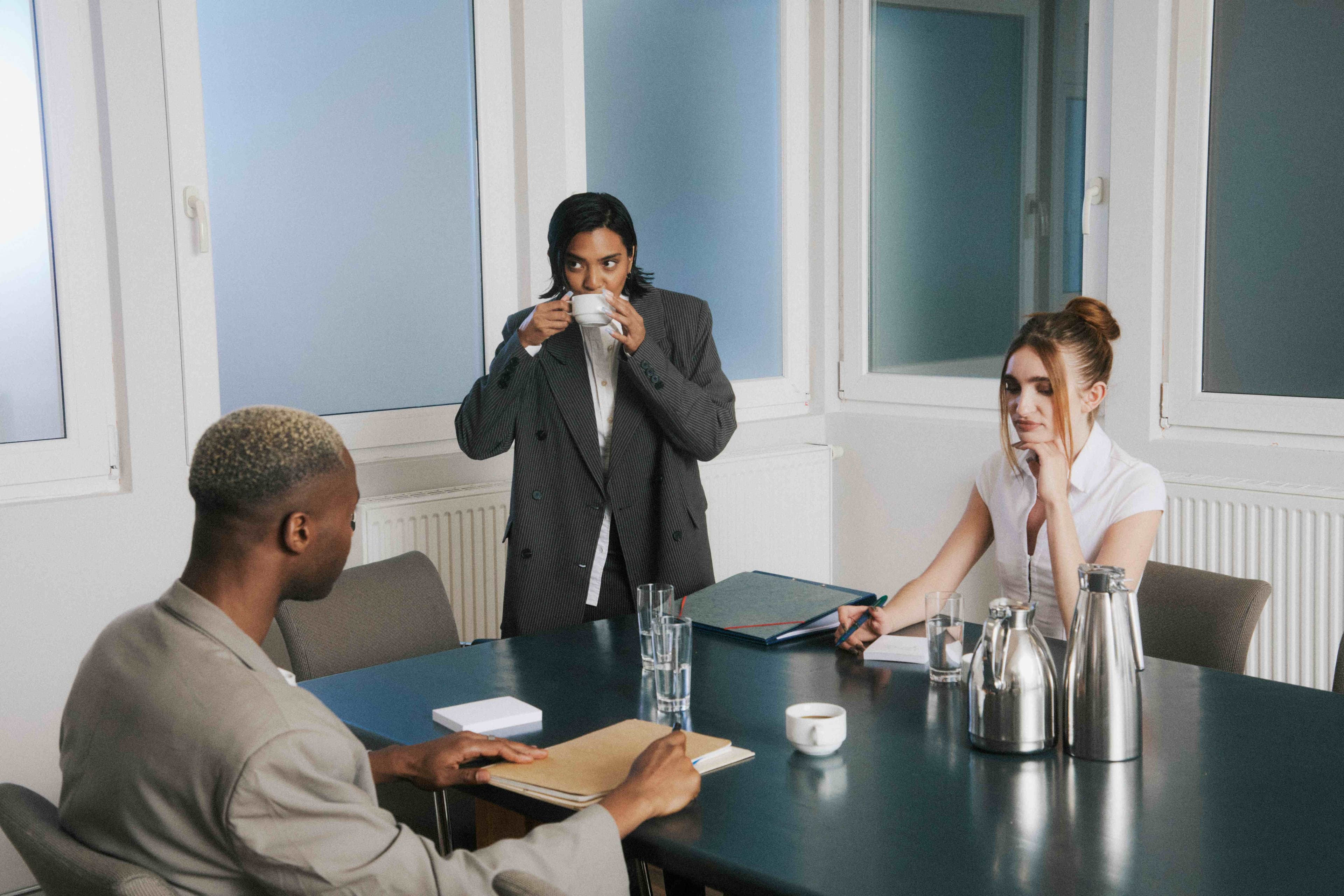 A meeting room with a colleague sipping coffee.