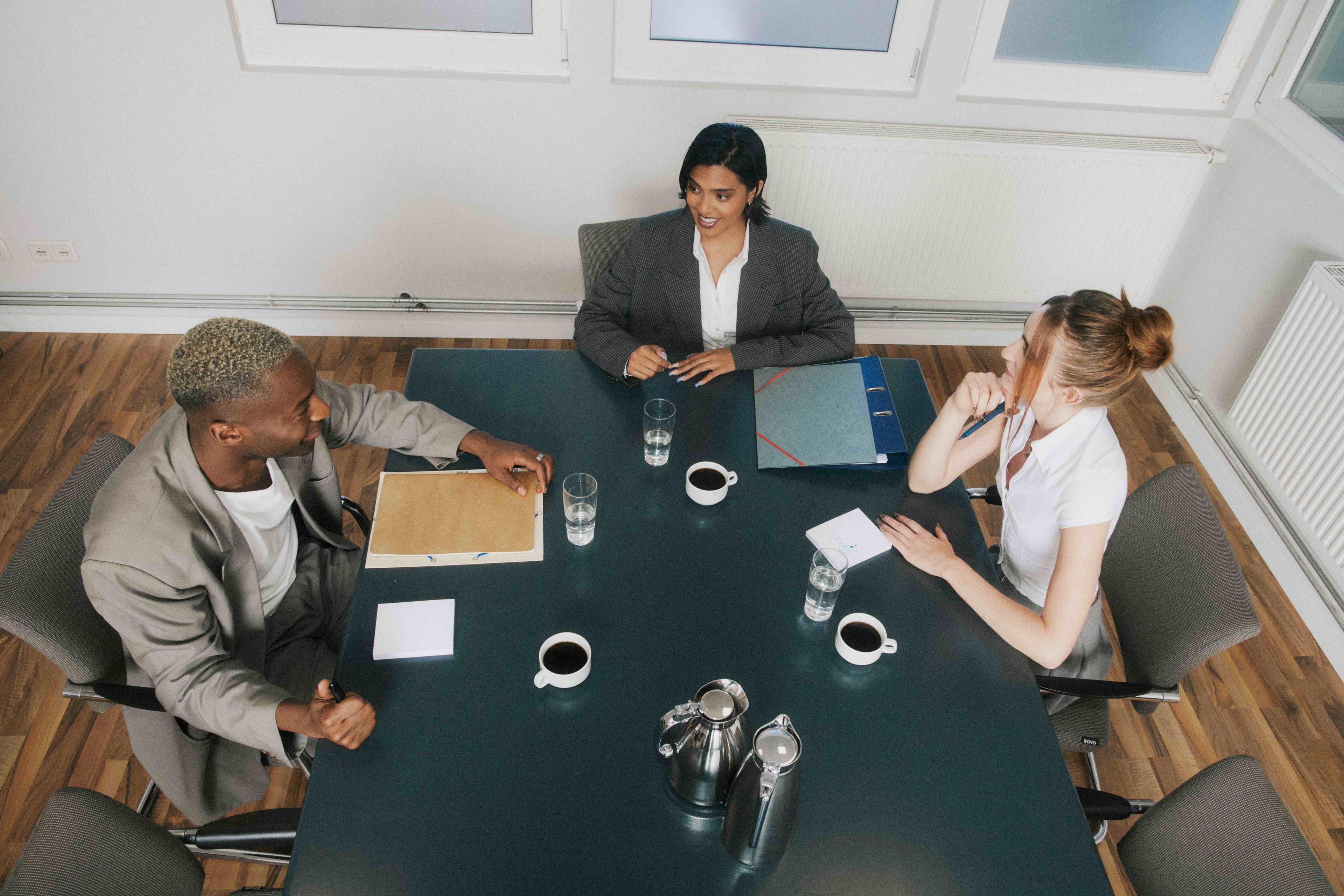 Three colleagues reviewing documents together around a meeting table